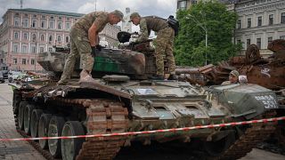 Sappers inspect a damaged Russian tank installed as a symbol of war in central Kyiv