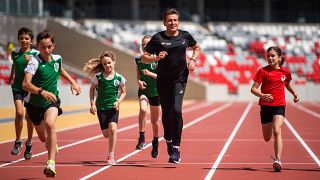 A WA elnöke, Sebastian Coe (középen) gyerekekkel fut a budapesti atlétikai világbajnokság futópályáján a Nemzeti Atlétikai Központban 2023.06.15-én.