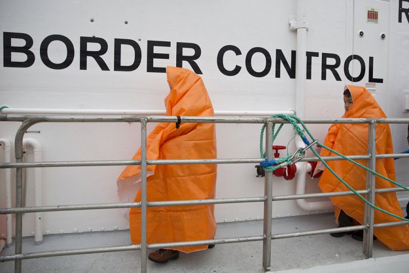 İki çocuk, Yunanistan'ın Midilli adası kıyılarında kurtarıldıktan sonra Norveç Frontex devriye gemisine biniyor