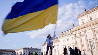 A woman waves a Ukrainian flag as she attends a protest against the war in Ukraine held in Berlin.