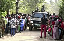 Security forces drive past a crowd of people gathered outside the Lhubiriha Secondary School following an attack in Mpondwe, Uganda, Saturday, June 17, 2023