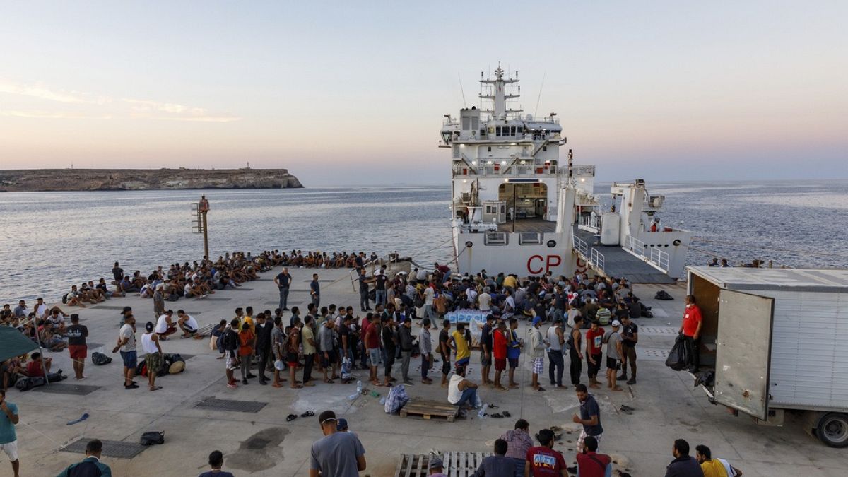 FILE - Migrants wait to board an Italian Coast Guard ship off the Sicilian Island of Lampedusa, Italy, August 3rd, 2022.