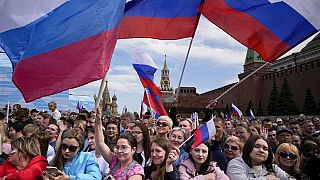 Thousands of people wave Russian national flags as they gather on Red Square to watch a concert dedicated to the Day of Russia in Moscow, Russia, Sunday, June 11, 2023.