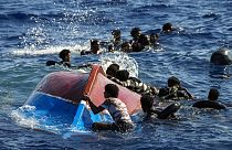 Migrants swim next to their overturned wooden boat during a rescue operation by Spanish NGO Open Arms at south of the Italian Lampedusa island at the Mediterranean sea.