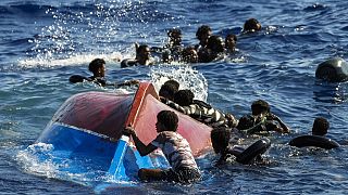 Migrants swim next to their overturned wooden boat during a rescue operation by Spanish NGO Open Arms at south of the Italian Lampedusa island at the Mediterranean sea.
