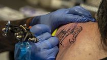 Henk Schiffmacher's needle whirrs as he tattoos the lines of am elephant on Lilian Rachmaran's back in Amsterdam, Monday, June 19, 2023