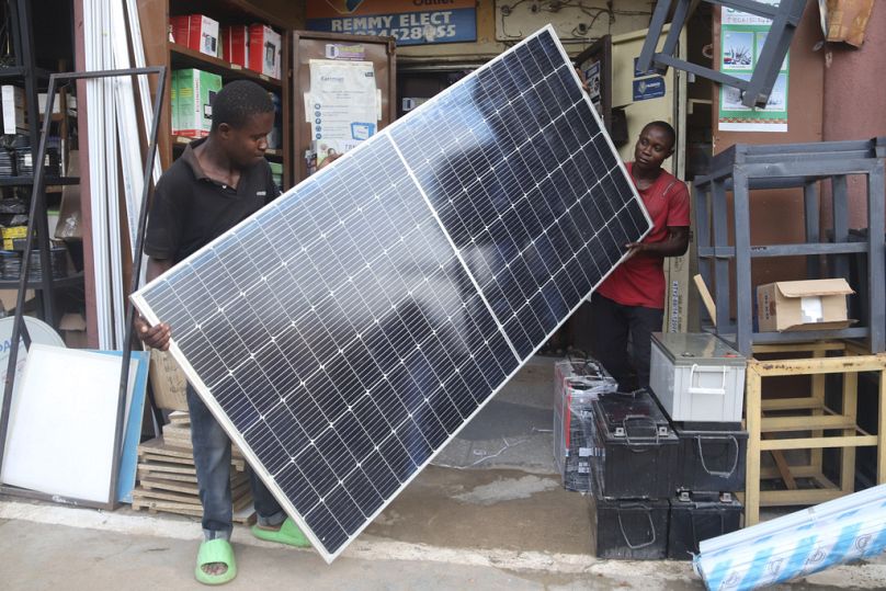 Men display a solar panel for sale at a shop in Abuja, June 2023