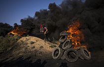 Palestinians burn tires and wave the national flag during a protest against an Israeli military raid in the West Bank city of Jenin, along the border fence with Israell.