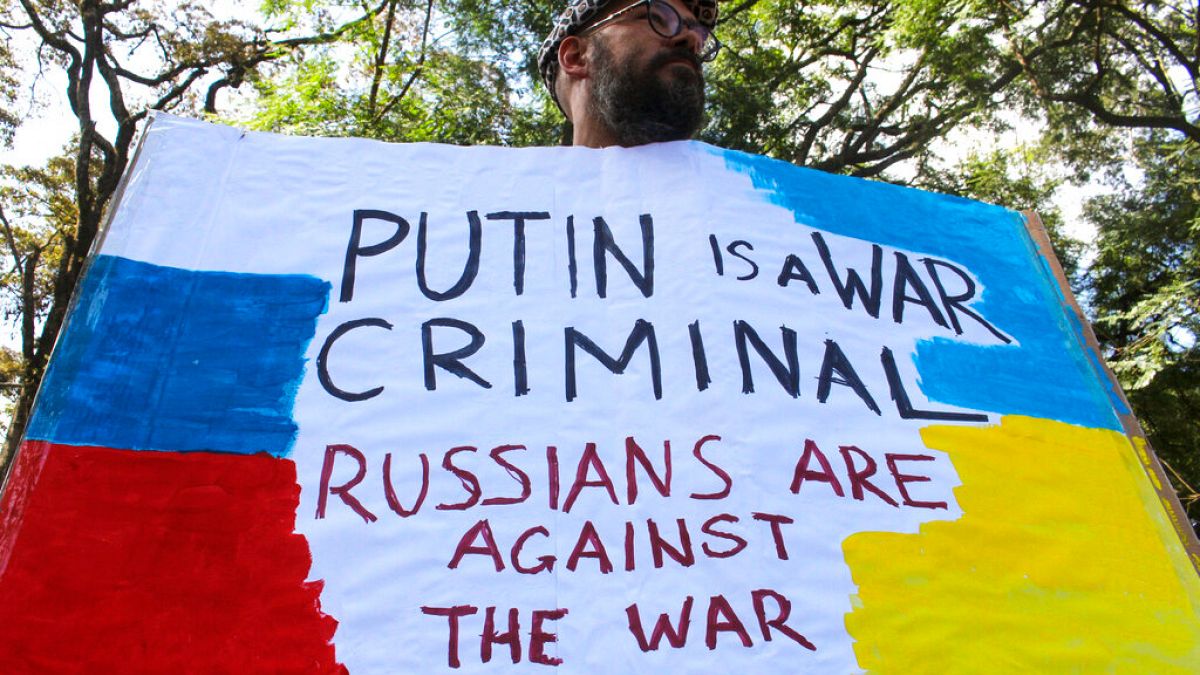Un manifestant tient une pancarte lors d'une petite manifestation contre l'invasion de l'Ukraine par la Russie, devant l'ambassade russe à Nairobi au Kenya, samedi 26 février 
