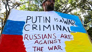 A protestor holds a placard at a small demonstration against Russia's invasion of Ukraine, in front of the Russian embassy in Nairobi Kenya, Saturday, Feb. 26, 2022.