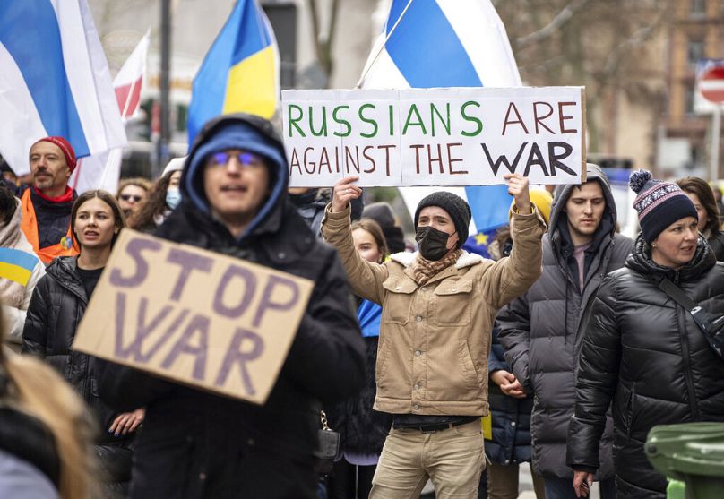 FILE - A man in a peace march holds a poster with the slogan "Russians are against the war" near the Russian Consulate General cordoned off by police in Germany 2/5/22.