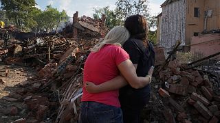 FILE: Ukrainian women hug in front of a building destroyed during a missile strike in Kharkiv, Ukraine, Thursday, Aug. 18, 2022.