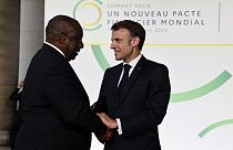 French President Emmanuel Macron (R) and South Africa's President Matamela Cyril Ramaphosa greet at the Palais Brogniart for the New Global Financial Pact Summit in Paris.