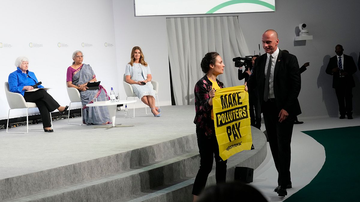 Ativista interrompe evento paralelo e exibe cartaz onde se lê "façam os poluidores pagar"