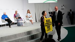 Ativista interrompe evento paralelo e exibe cartaz onde se lê "façam os poluidores pagar"