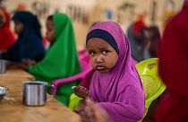 A child eats at a school in Dollow, Somalia, on Sept. 19, 2022. In many Middle Eastern and African nations, climatic shocks kill hundreds and displace thousands every year.