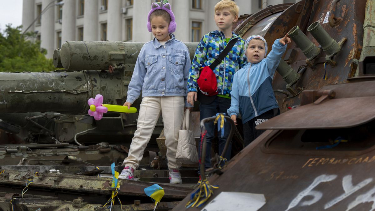 Kinder auf einem ausgebrannten russischen Panzer in Kiew, Ukraine, 11. Juni 2023.