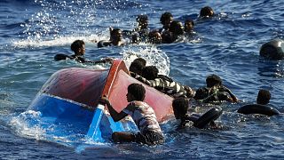 Tavalyi felvétel: afrikai migránsok a felfordult csónakjuk mellett Lampedusánál