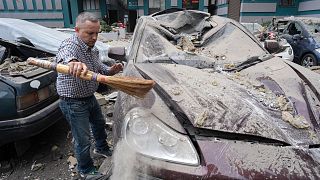 Un homme nettoie une voiture endommagée après une attaque russe dans le quartier des immeubles d'habitation à Kyiv, Ukraine, samedi 24 juin 2023.