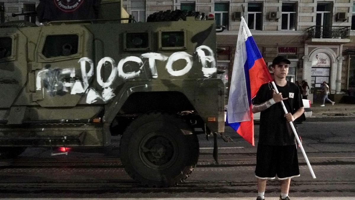Homem segura bandeira russa em frente a viatura do grupo Wagner em Rostov