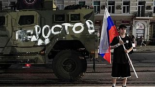 Homem segura bandeira russa em frente a viatura do grupo Wagner em Rostov
