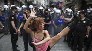 فتاة ترقص ومن خلفها يظهر رجال الشرطة خلال مسيرة دعما للمثليين_اسطنبول