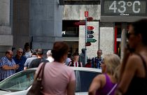 People walk near a sign indicating 43 degrees Celsius as near record temperatures hit Bilbao, Spain in 2022. 