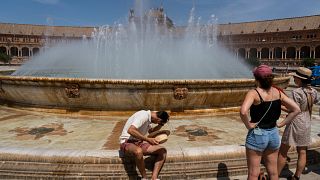 Ein Mann erfrischt sich an einem Brunnen in Sevilla, Spanien, 27. April 2023. 