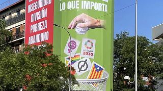 A far-right Vox party sign hangs in Madrid showing a hand dropping cards with symbols representing feminism and the LGBTQ+ community