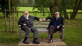 Two men sit on a bench on the periphery of the Hampstead Heath Heritage Festival, which is a celebration of old England on Hampstead Heath in London, Sunday, Oct. 7, 2012.