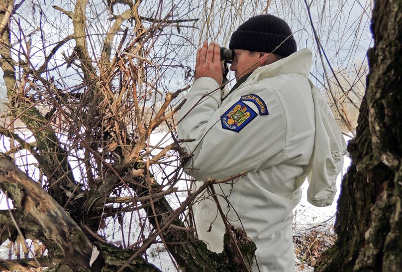 a Romanian border policeman watching through binoculars over no mans land between Ukraine and Romania near Halmeu, January 2013