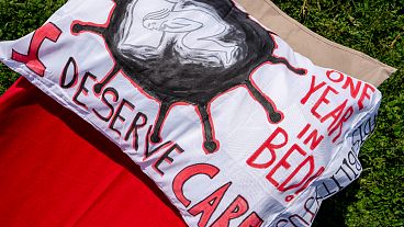 A pillow is decorated with the words "I Deserve Care" and "One Year in Bed!" as advocates for people suffering from long COVID host an installation in Washington.