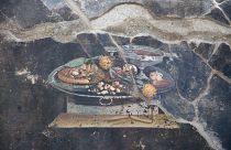Archaeologists carefully excavate the wall where the ‘pizza’ fresco was found on the northeastern end of the archaeological park
