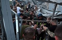 Rescuers and volunteers carry a rescued woman from the rubble after Russian missile strike hit a restaurant and several houses in Kramatorsk