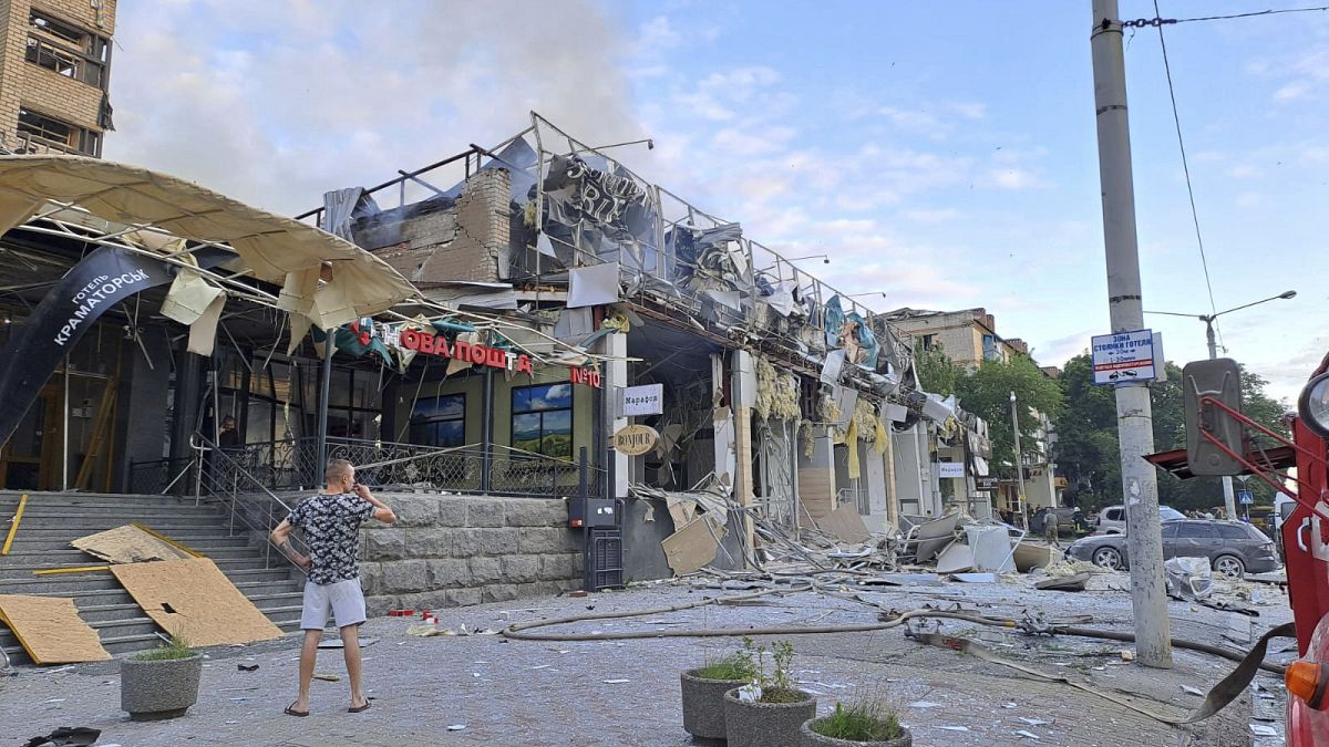 Un hombre se encuentra en una calle frente a una tienda y restaurante RIA Pizza destruida por un ataque ruso en Kramatorsk