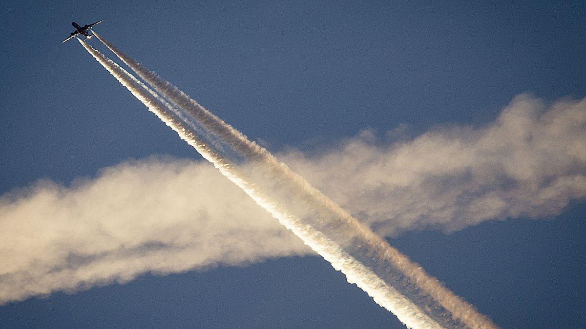 An aircraft crosses the vapor trails of another plane over Frankfurt, Germany. Research into technology to combat climate change remains controversial.