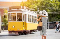 A tourist takes a photo of a tram in Lisbon