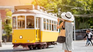 A tourist takes a photo of a tram in Lisbon