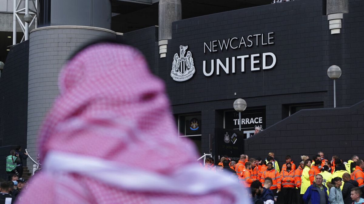A man with a Saudi Arabian headdress pases by St. James' Park in Newcastle. 