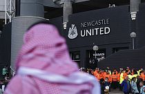 A man with a Saudi Arabian headdress pases by St. James' Park in Newcastle. 