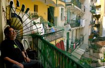 Fernando Uceta utiliza una mochila concentradora de oxígeno portátil con batería para respirar mientras está sentado en el balcón de su casa durante la primera ola de calor del verano, en Barcelona.