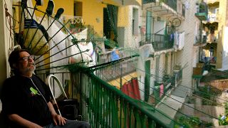 Fernando Uceta utiliza una mochila concentradora de oxígeno portátil con batería para respirar mientras está sentado en el balcón de su casa durante la primera ola de calor del verano, en Barcelona.