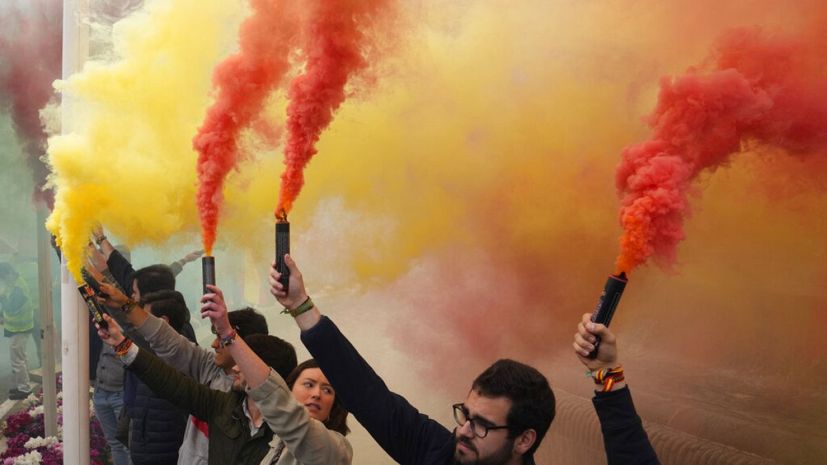 Youths hold lit flares during the Spanish national anthem at the end of a rally by the extreme right-wing party VOX in Madrid.