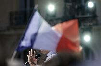 Behind a French flag, French President and centrist candidate Emmanuel Macron speaks during a campaign rally, Saturday, April 16, 2022 in Marseille, southern France.
