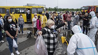 Trabajadores de emergencias ucranianos con trajes de protección radiológica comprueban el nivel de radiación de pasajeros en Zaporiyia, Ucrania, el jueves 29 de junio de 2023.
