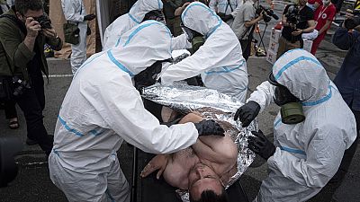 عمال الطوارئ الأوكرانيون الذين يرتدون بدلات واقية من الإشعاع يغطون رجلًا ببطانية أثناء التدريب في زاباروجيا، أوكرانيا، الخميس 29 يونيو 2023.