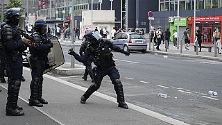 A police officer prepares to send a tear gas canister after a march for Nahel, Thursday, June 29, 2023 in Nanterre, outside Paris.