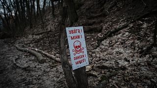 Um cartaz indica a presença de minas terrestres na posição de uma unidade de voluntários ucranianos num subúrbio de Kiev, em 28 de fevereiro de 2023\. 