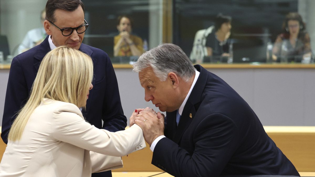 Orban bacia le mani di Giorgia Meloni, sotto lo sguardo di Morawiecki.(Bruxelles, 30.6.2023)