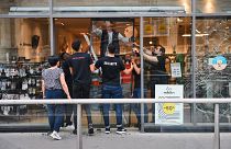 Сотрудники магазина Monoprix в центра Лиона снимают разбитые стеклянные двери